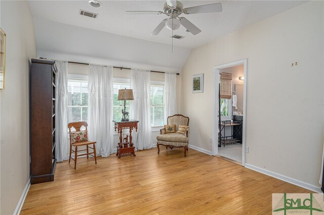 living area featuring lofted ceiling, ceiling fan, and light wood-type flooring