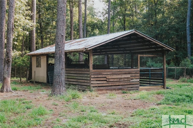 view of outbuilding featuring a wooded view, an exterior structure, and an outbuilding