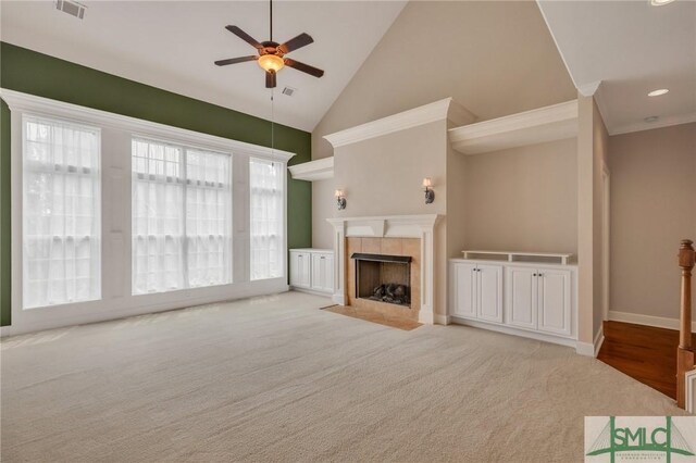 unfurnished living room with a fireplace, light colored carpet, high vaulted ceiling, and ceiling fan