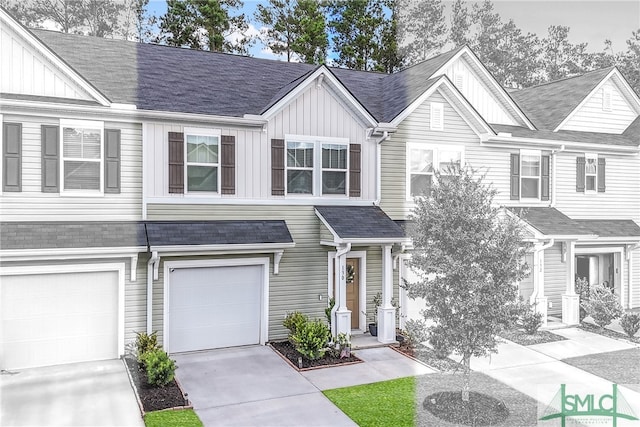 view of property with board and batten siding, a shingled roof, driveway, and a garage