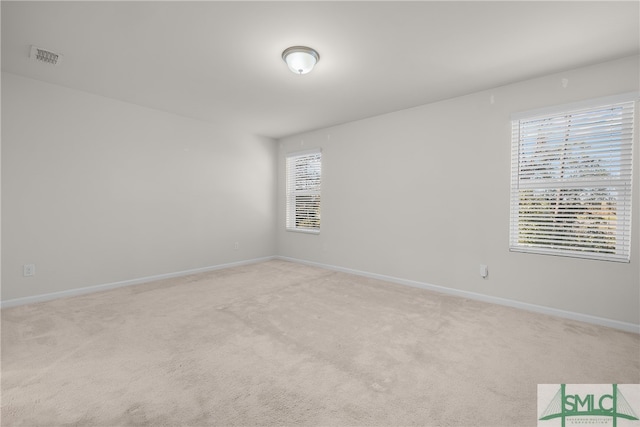 spare room with visible vents, light colored carpet, and baseboards