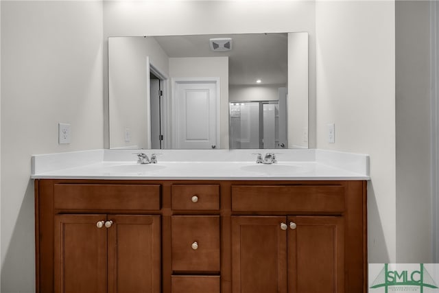 full bathroom with double vanity, visible vents, a shower with shower door, and a sink