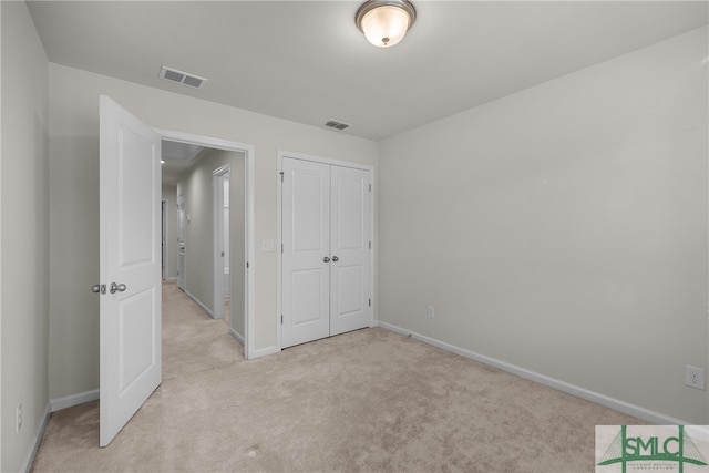 unfurnished bedroom featuring visible vents, light carpet, a closet, baseboards, and attic access