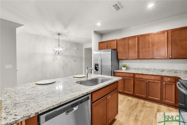 kitchen with visible vents, an island with sink, a sink, stainless steel appliances, and light wood-style floors