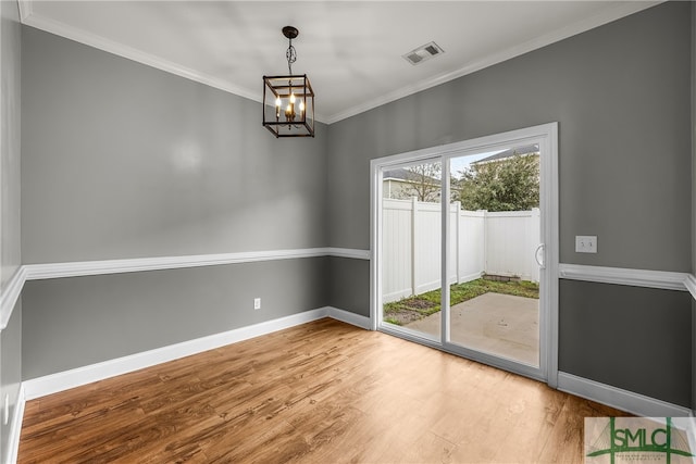 unfurnished room with hardwood / wood-style flooring, ornamental molding, and an inviting chandelier