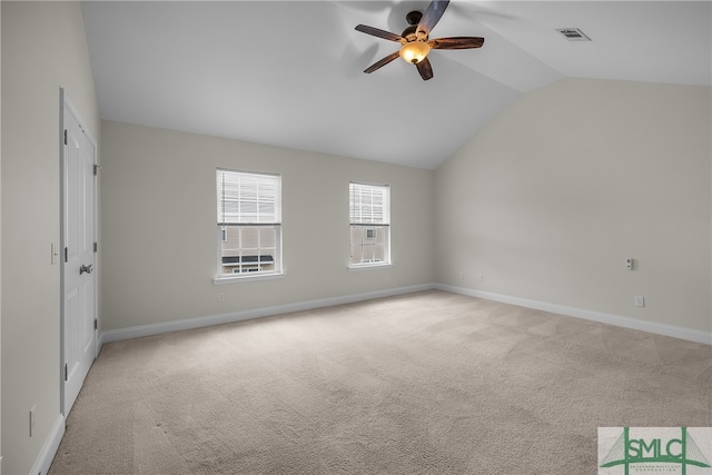 spare room with ceiling fan, light colored carpet, and vaulted ceiling