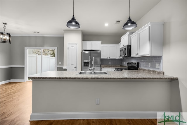 kitchen featuring appliances with stainless steel finishes, light hardwood / wood-style flooring, white cabinetry, and hanging light fixtures