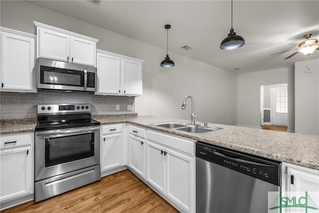 kitchen with sink, white cabinets, hanging light fixtures, and appliances with stainless steel finishes