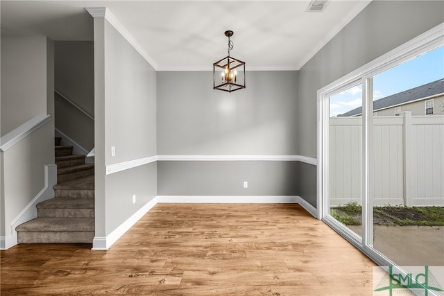 unfurnished dining area featuring light hardwood / wood-style floors, crown molding, and a chandelier