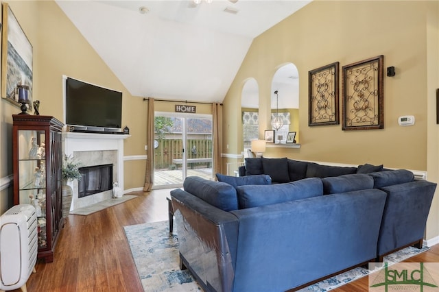 living room with a tiled fireplace, wood-type flooring, and lofted ceiling