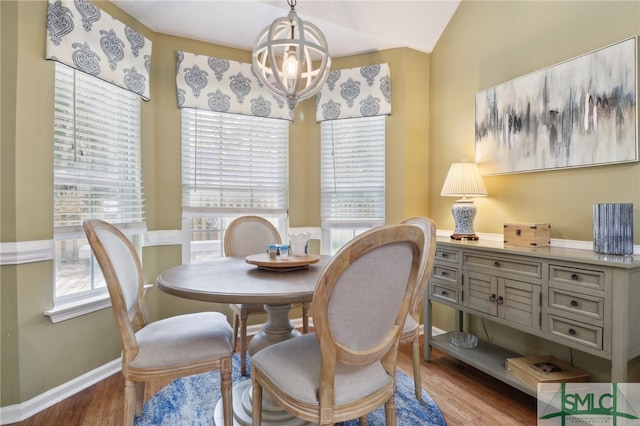 dining area with an inviting chandelier, lofted ceiling, and light hardwood / wood-style flooring