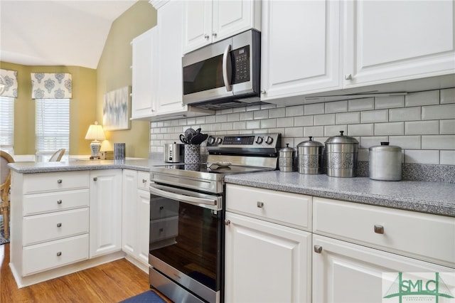 kitchen with lofted ceiling, white cabinetry, and stainless steel appliances