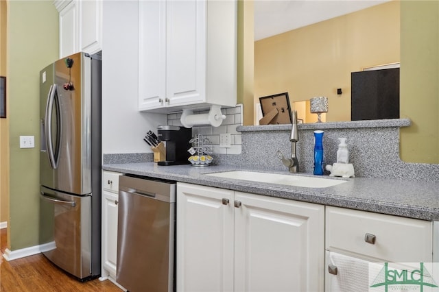 kitchen with white cabinets, appliances with stainless steel finishes, hardwood / wood-style flooring, and sink