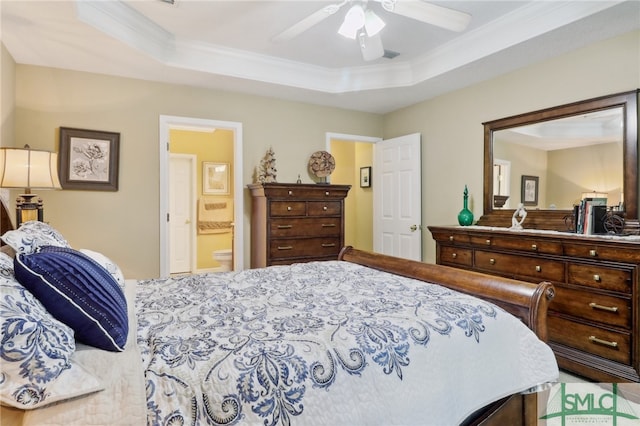 bedroom with a tray ceiling, ensuite bathroom, ceiling fan, and ornamental molding