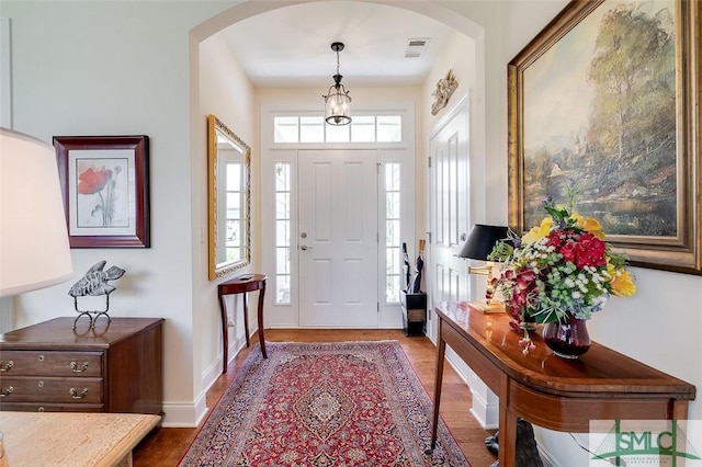 entryway featuring arched walkways, visible vents, baseboards, and wood finished floors