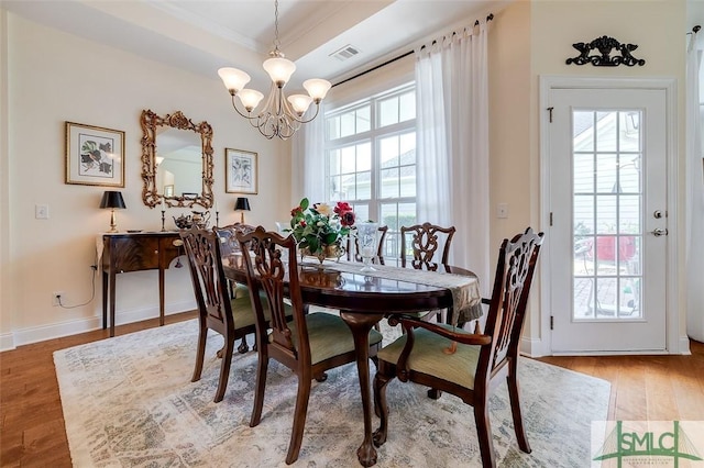 dining space featuring visible vents, a notable chandelier, baseboards, and wood finished floors