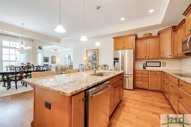 kitchen featuring stainless steel appliances, a kitchen island with sink, a sink, and light wood-style flooring