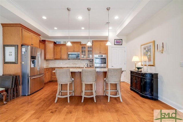 kitchen with light wood-style flooring, stainless steel appliances, crown molding, and a raised ceiling