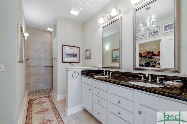 full bath featuring a walk in shower, double vanity, a sink, and tile patterned floors