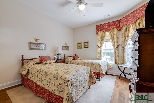 bedroom with a ceiling fan, wood finished floors, visible vents, and baseboards