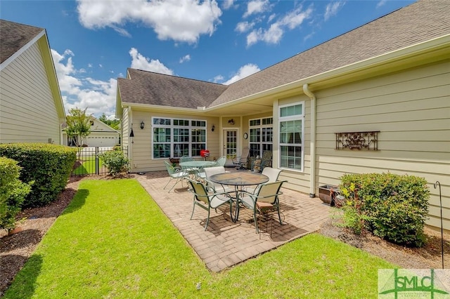 rear view of house with a shingled roof, fence, a lawn, and a patio