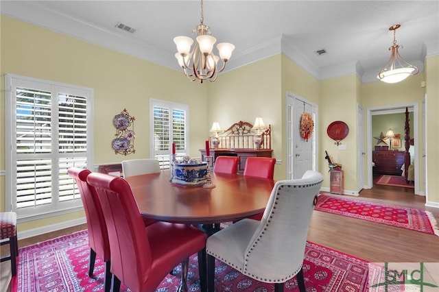 dining room featuring a chandelier, visible vents, crown molding, and wood finished floors