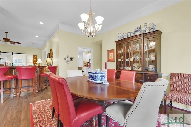 dining area featuring ceiling fan with notable chandelier, light hardwood / wood-style floors, and ornamental molding