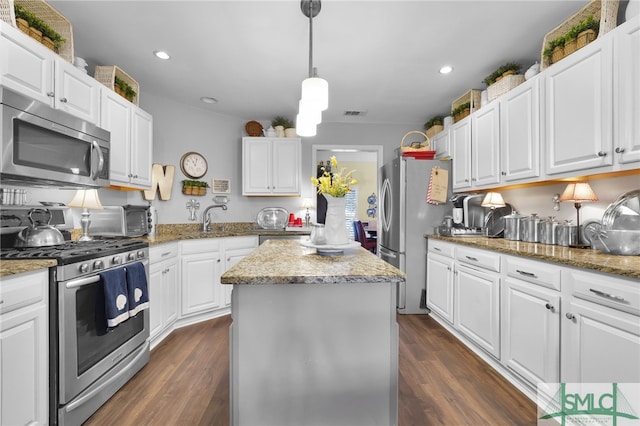 kitchen featuring decorative light fixtures, appliances with stainless steel finishes, light stone counters, dark hardwood / wood-style flooring, and white cabinetry