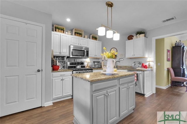 kitchen with dark wood-style floors, a center island, stainless steel appliances, visible vents, and white cabinets