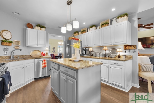 kitchen with a center island, ceiling fan with notable chandelier, light stone countertops, stainless steel appliances, and white cabinetry