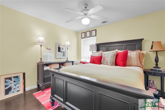 bedroom with a textured ceiling, dark wood-type flooring, and ceiling fan