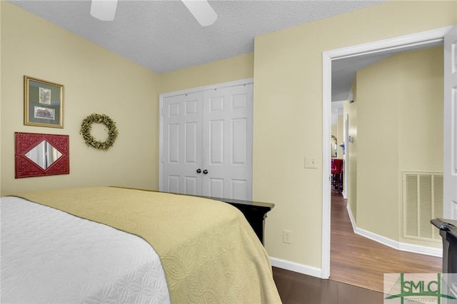 bedroom with dark wood-type flooring, a closet, ceiling fan, and a textured ceiling