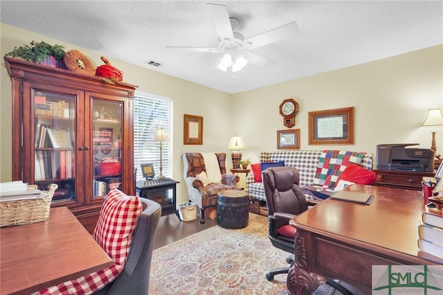 home office with visible vents, ceiling fan, a textured ceiling, and wood finished floors