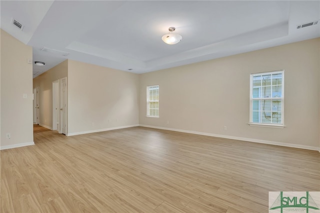 unfurnished room with a tray ceiling and light hardwood / wood-style floors