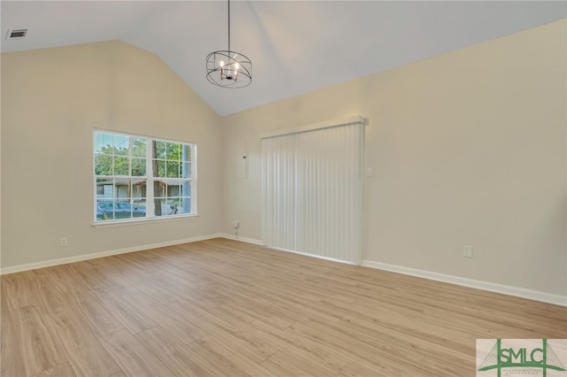 spare room with an inviting chandelier, light hardwood / wood-style floors, and vaulted ceiling