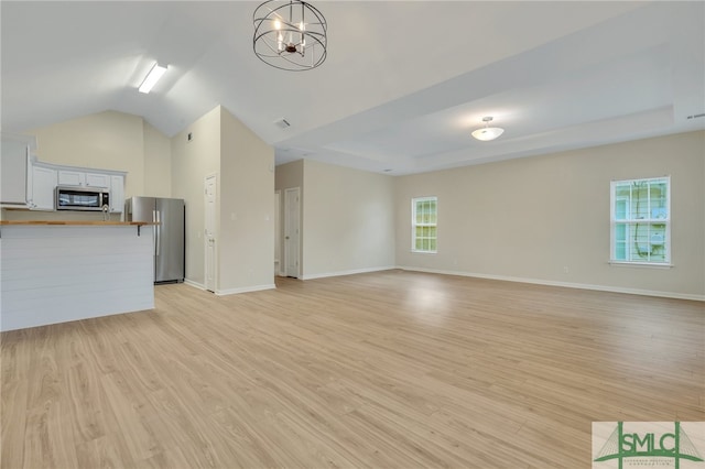 unfurnished living room with light hardwood / wood-style flooring, vaulted ceiling, and an inviting chandelier