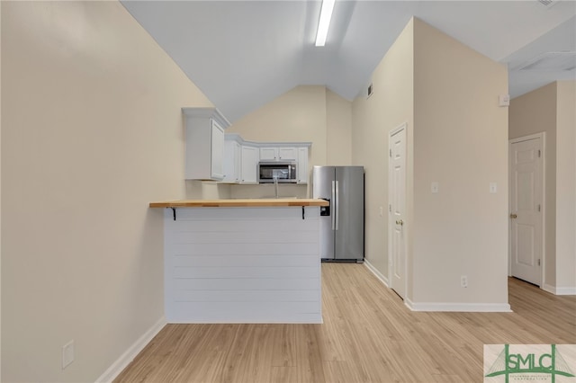 kitchen featuring light hardwood / wood-style flooring, a breakfast bar, stainless steel appliances, kitchen peninsula, and white cabinets