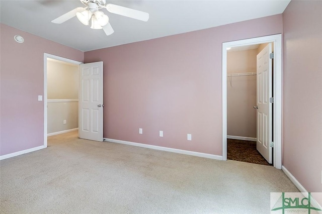 unfurnished bedroom with a spacious closet, ceiling fan, a closet, and light colored carpet