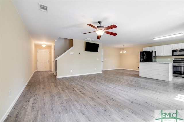 unfurnished living room featuring light wood-type flooring and ceiling fan with notable chandelier