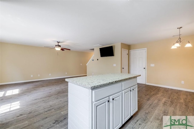 kitchen with decorative light fixtures, light wood-type flooring, ceiling fan with notable chandelier, white cabinets, and a center island