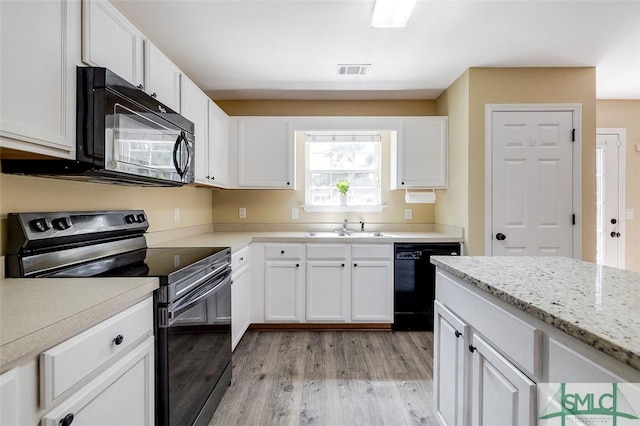 kitchen featuring black appliances, sink, white cabinetry, light hardwood / wood-style flooring, and light stone countertops