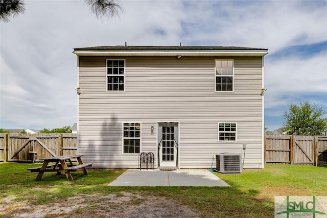 rear view of property featuring central AC unit, a lawn, and a patio