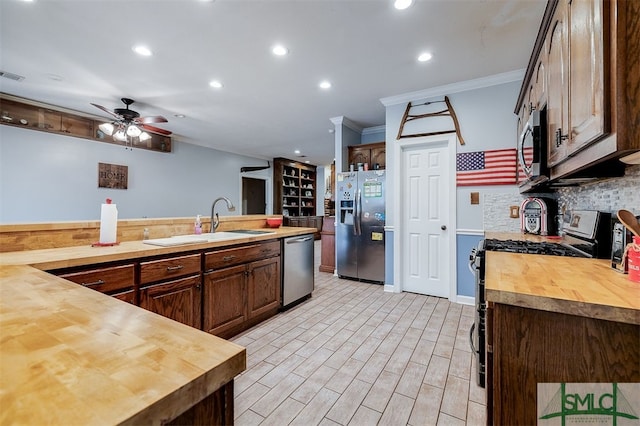 kitchen featuring crown molding, appliances with stainless steel finishes, sink, butcher block countertops, and ceiling fan