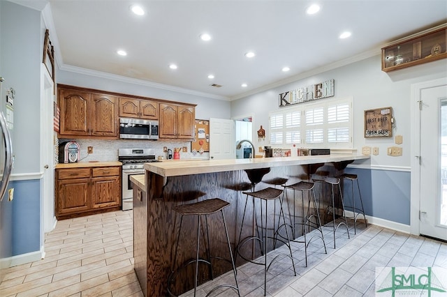 kitchen featuring a kitchen bar, light hardwood / wood-style flooring, ornamental molding, and appliances with stainless steel finishes