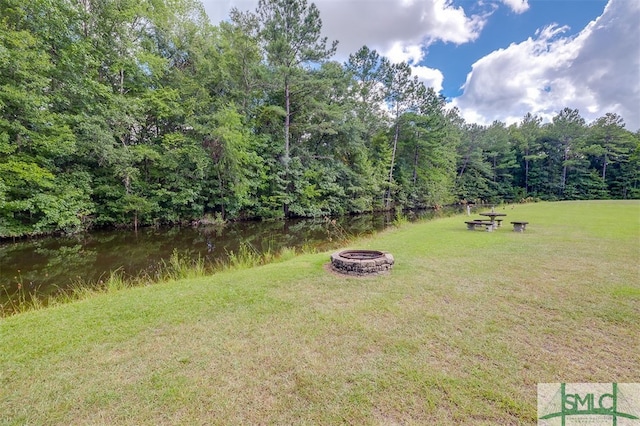 view of yard with an outdoor fire pit and a water view