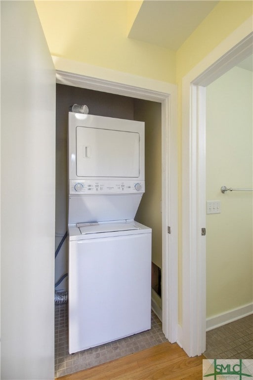 laundry area with hardwood / wood-style floors and stacked washing maching and dryer