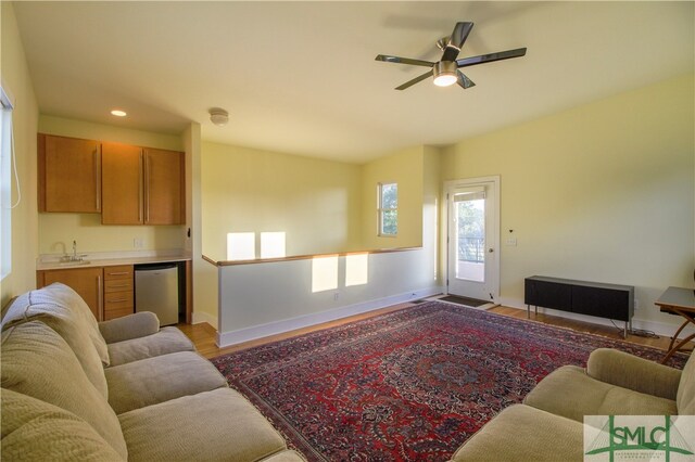 living room featuring sink, light wood-type flooring, and ceiling fan