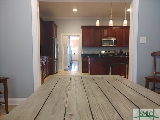 kitchen with hanging light fixtures, stainless steel appliances, light wood-type flooring, and ornamental molding