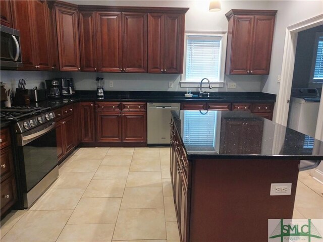 kitchen with sink, a center island, light tile patterned floors, and appliances with stainless steel finishes