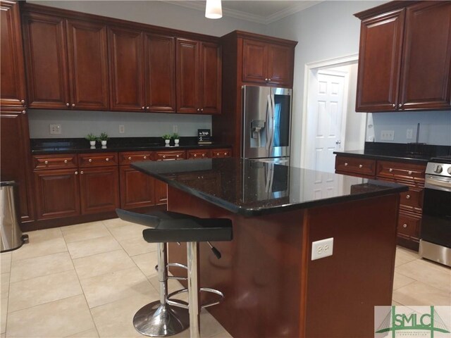 kitchen with stove, stainless steel fridge, ornamental molding, a kitchen island, and a breakfast bar area